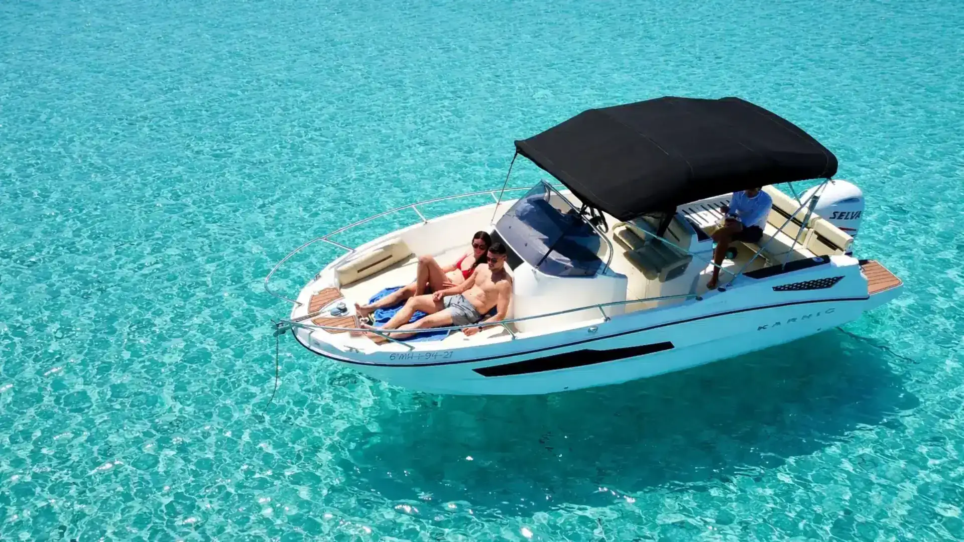 Lancha con patrón navegando por aguas turquesas de Menorca